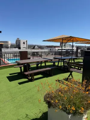 two picnic tables with an umbrella on a roof at Depto Céntrico, Cochera, Pile, Terraza in Villa Carlos Paz