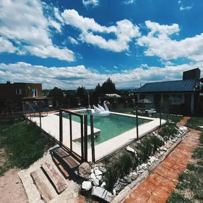 a swimming pool with a swan statue in a yard at Cabañas Las serranitas 2 in Villa Parque Siquiman