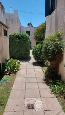 a walkway between two buildings with bushes on each side at Castillo Del Lago - Carlos Paz - D18 in Villa Carlos Paz