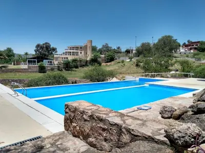 a large swimming pool with blue water in a resort at Casa Carlos Paz Terrazas del Lago in Villa Carlos Paz