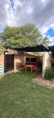 a patio with a table and red chairs in a yard at Dpto Marina in Villa Cura Brochero