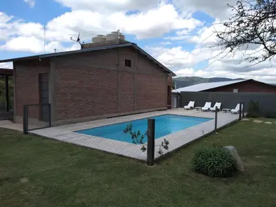 a swimming pool in a yard next to a house at Cabañas Quimera in Santa Rosa de Calamuchita