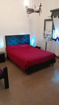 a bedroom with a large bed with a red bedspread at Cazona Villa Carmen in Villa Carlos Paz