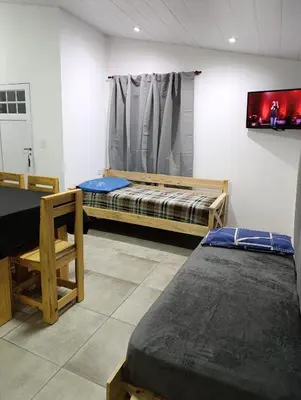 a room with two beds and a tv on the wall at Sinaí Apart in Santa Rosa de Calamuchita