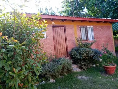 a small brick house with a door in a garden at Casa Sol Y Rio, LOFT MONOAMBIENTE in Mina Clavero