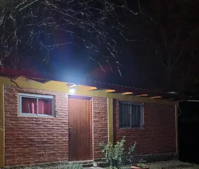 a brick house with a wooden door at night at Casa Sol Y Rio, LOFT MONOAMBIENTE in Mina Clavero
