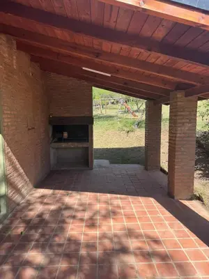 a brick patio with a wooden roof and a fireplace at Cabañas De La Colina in Villa General Belgrano