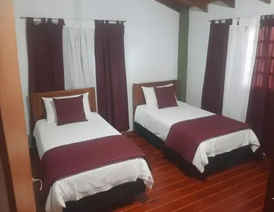 two beds in a room with red curtains at La casa de milac in Mina Clavero