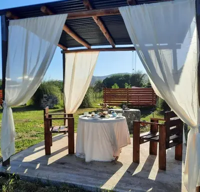 a table and chairs under a pavilion with white curtains at CabañaPaz in Santa Rosa de Calamuchita