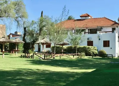 a house with a yard with picnic tables and trees at Hosteria de los Césares in Merlo