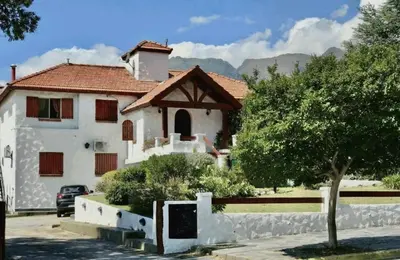 a white house with a tree in front of it at Hosteria de los Césares in Merlo