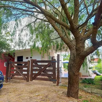 a wooden fence with a tree in front of a house at Casa Minimalista con Pileta Privada en el mejor lugar de Cabalango in Cavalango