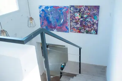 a dog standing under a glass staircase with two paintings at Casa Potrero de Garay in La Estancia