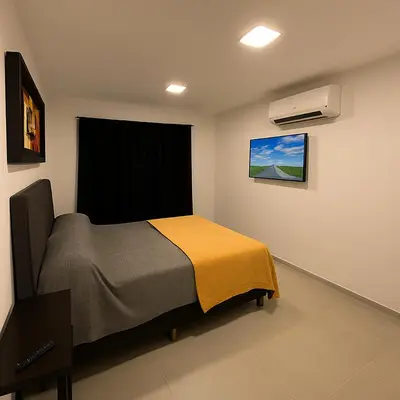 a bedroom with a bed and a air conditioner at Departamentos Cañitas in Malagueño