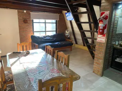 a dining room with a table and a living room at Complejo alpinas del valle in Santa Rosa de Calamuchita