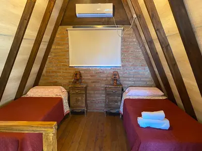 a attic room with two beds and a window at Complejo alpinas del valle in Santa Rosa de Calamuchita