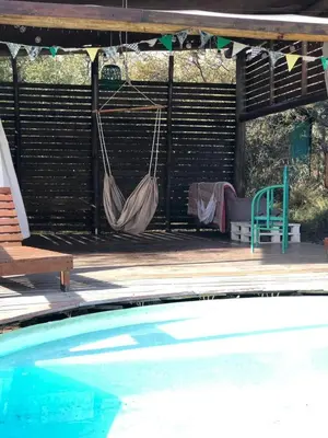 two hammocks hanging from a pergola next to a pool at Glamping Traslasierra Carpa Sur in San Javier
