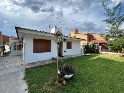 a small white house with a grass yard at Casa Jaz in Villa Carlos Paz