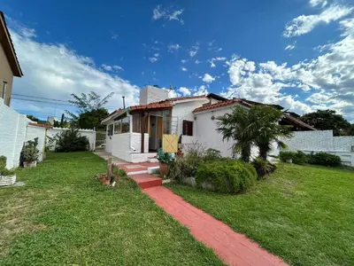 a small white house with a grass yard at Casa Jaz in Villa Carlos Paz