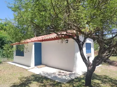 a small white shed with a red roof next to a tree at La Calma, casa de Rio in Los Reartes