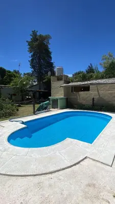 a large blue swimming pool in front of a house at Casa en complejo con pileta compartida in San Roque