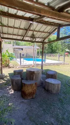 a group of tree stump benches under a pergola at Casa en complejo con pileta compartida in San Roque
