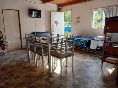 a room with a table and chairs and a bed at La Gringa in Villa Parque Siquiman