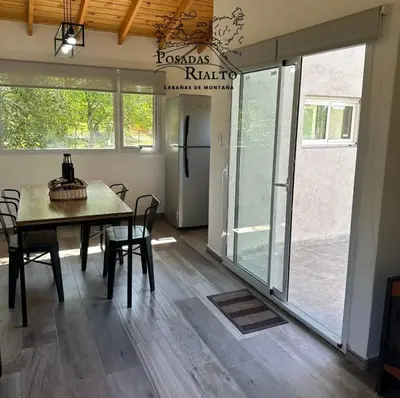a dining room with a table and chairs and sliding glass doors at cabañas RIALTO in Villa Amancay