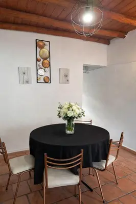 a vase of flowers on a table with chairs at Viva raíz in Nono