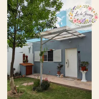 a blue house with a white door and a tree at Lo de Juany in Villa Cura Brochero