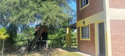 a tree next to a building with a fence at Los algarrobos in Mina Clavero
