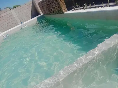 a swimming pool filled with water next to a building at Casa con pileta privada para 5 in Villa Carlos Paz