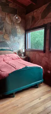 a bedroom with a large bed with a stone wall at Tierra de Sueños in Santa Rosa de Calamuchita
