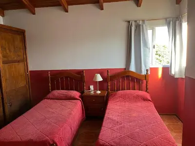 two beds in a bedroom with red sheets and a window at La soñada San Antonio de Arredondo in San Antonio de Arredondo
