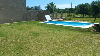 a swimming pool in a yard with a grass field at Cabaña los algarrobos in Mina Clavero