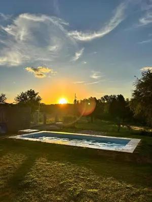 a swimming pool with the sunset in the background at Cabaña los algarrobos in Mina Clavero