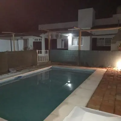 a swimming pool at night with a house in the background at Casa con pileta de uso exclusivo a 5 cuadras de McDonald's in Villa Carlos Paz