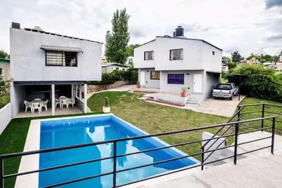 a villa with a swimming pool in front of a house at Monoambiente los ceibos in Villa Santa Cruz del Lago