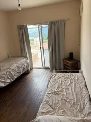 a bedroom with two beds and a sliding glass door at Depto Vista panoramica in Villa Carlos Paz