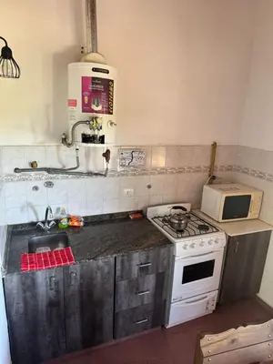 a kitchen with a stove and a microwave at Hostel Planeta Terminal VGB in Villa General Belgrano