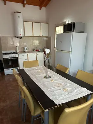 a kitchen with a table with chairs and a refrigerator at Alma ina in Villa Yacanto