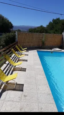 a row of yellow lounge chairs next to a swimming pool at Postal Serrana 1 in Villa Cura Brochero