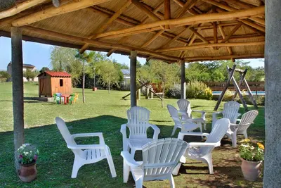 a group of white chairs under a pavilion with a playground at Cabañas Dolce Vita I in Los Reartes