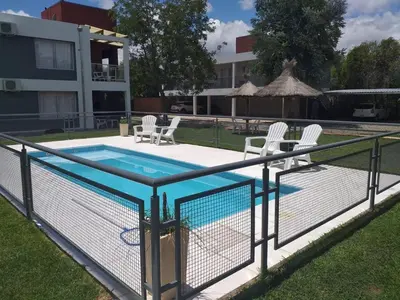 a fence around a swimming pool with two chairs at Abuela Mari Apart Cabaña in Villa Cura Brochero