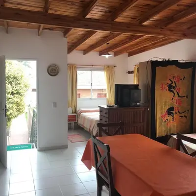 a room with two beds and a television and a table at Departamento Con Vistas a La Montaña in Villa Carlos Paz