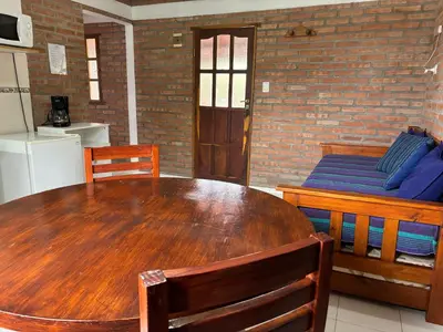 a dining room with a wooden table and a couch at Departamentos Los Álamos in Mina Clavero