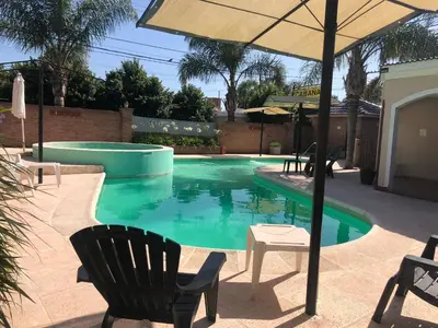 a swimming pool with two chairs and an umbrella at Cabañas Los Aromos in Embalse