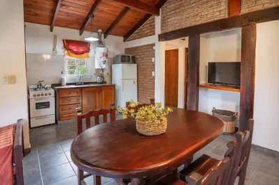 a kitchen with a wooden table with chairs and a kitchen with a refrigerator at El Portillo in Villa General Belgrano