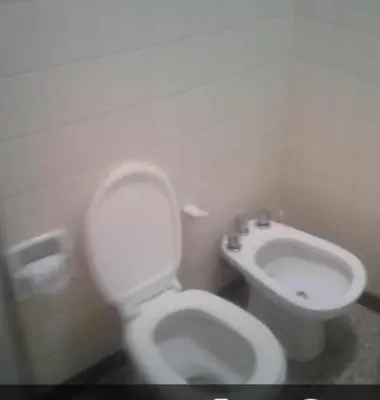 a bathroom with a white toilet and a sink at Dptos LOW COST in Mina Clavero