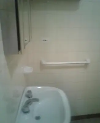 a white bathroom with a sink and a mirror at Dptos LOW COST in Mina Clavero